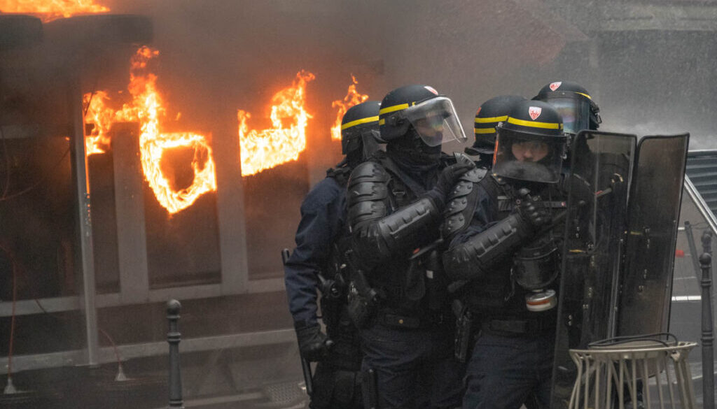 A fire breaks out behind riot police in Paris