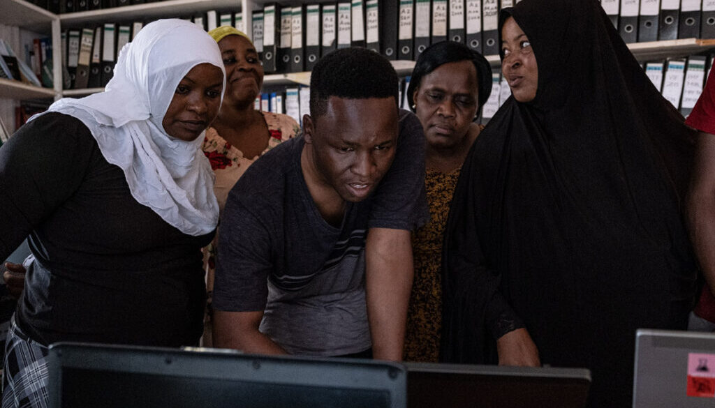 A group of women look at a laptop